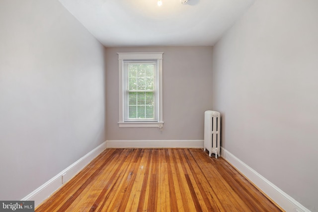 empty room with light hardwood / wood-style flooring and radiator heating unit