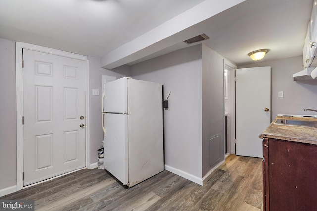 kitchen with dark brown cabinetry, white refrigerator, dark wood-type flooring, and sink