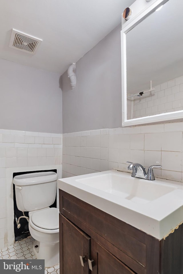 bathroom featuring tile walls, vanity, and toilet