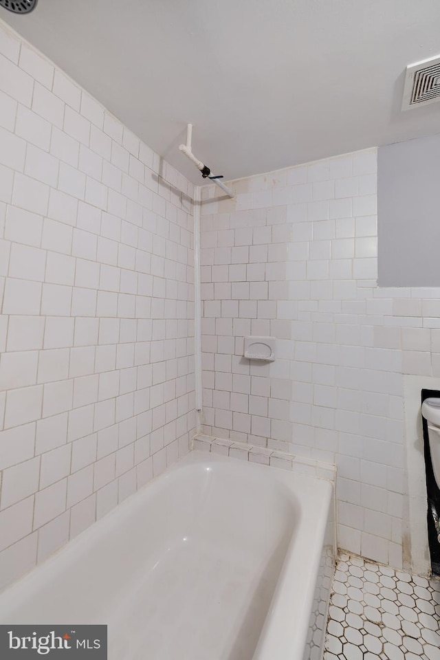 bathroom featuring tile patterned flooring, tile walls, and tiled shower / bath