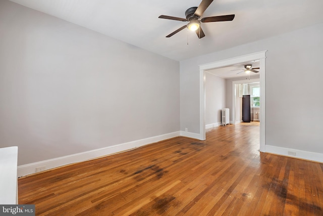 empty room with ceiling fan, radiator heating unit, and wood-type flooring