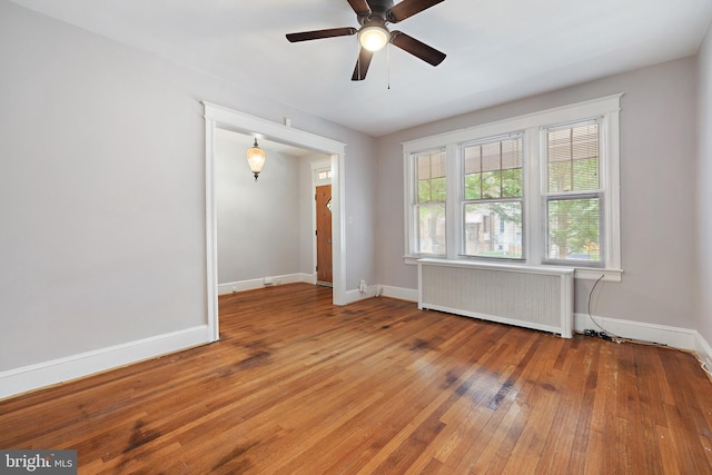 spare room featuring ceiling fan, radiator, and hardwood / wood-style flooring