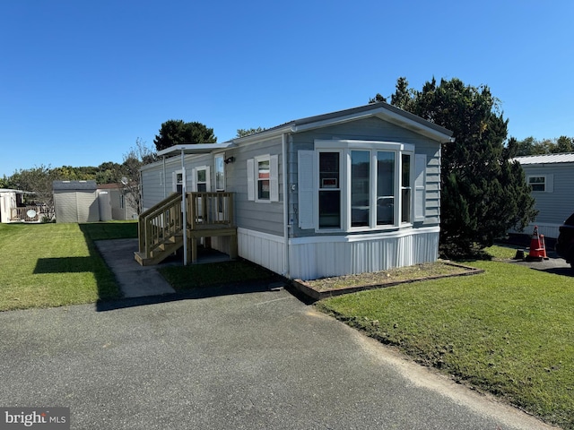 view of front of property featuring a storage shed and a front lawn