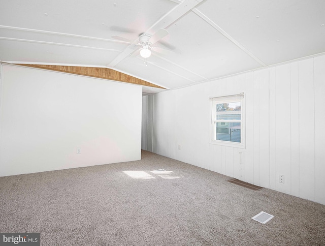 empty room with ceiling fan, wood walls, carpet, and lofted ceiling