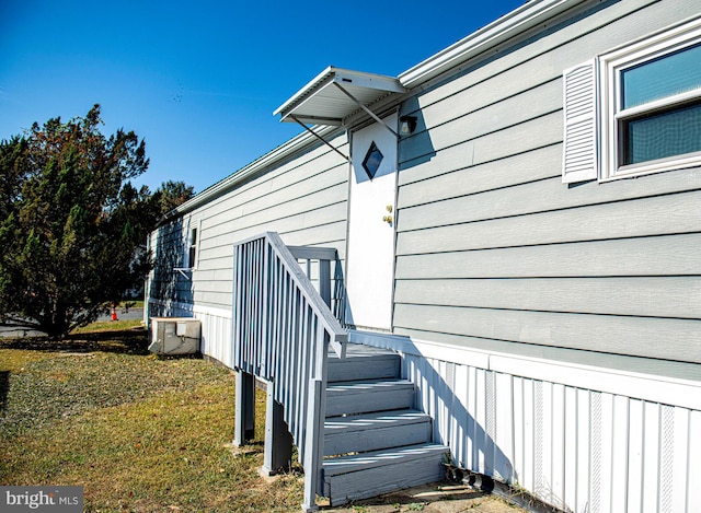 entrance to property featuring central air condition unit and a lawn