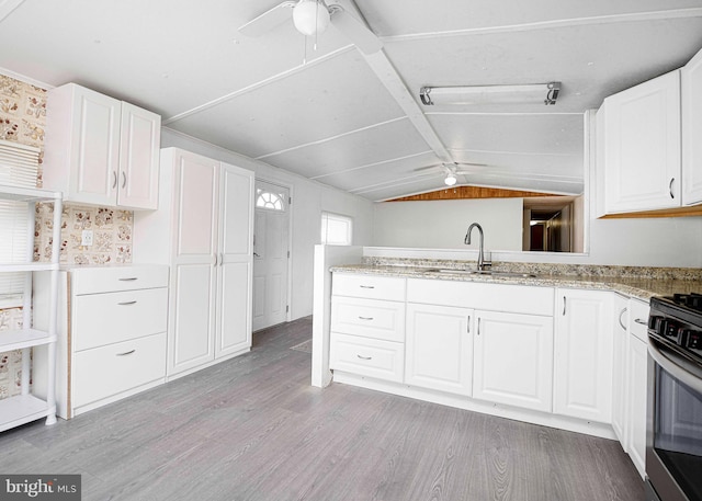 kitchen with sink, stainless steel range with electric stovetop, white cabinetry, lofted ceiling, and light hardwood / wood-style flooring