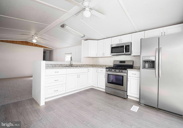 kitchen with lofted ceiling, appliances with stainless steel finishes, white cabinetry, light hardwood / wood-style flooring, and sink