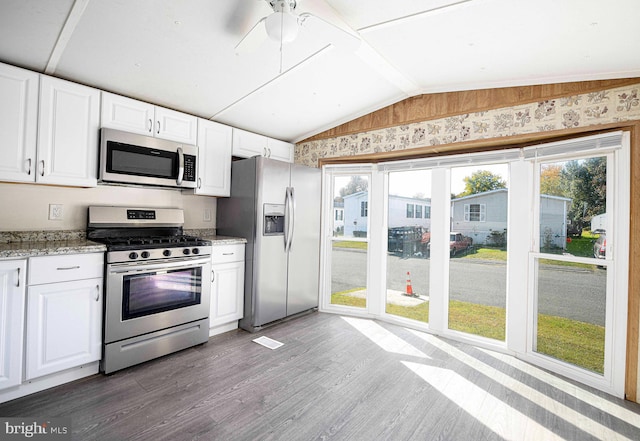 kitchen with light stone countertops, appliances with stainless steel finishes, dark hardwood / wood-style floors, and white cabinets