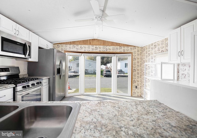 kitchen featuring light stone countertops, white cabinetry, ceiling fan, stainless steel appliances, and lofted ceiling