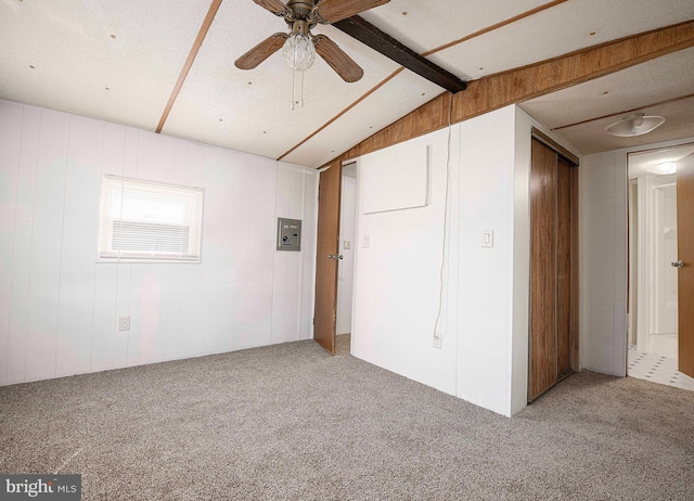 interior space featuring ceiling fan, lofted ceiling with beams, a textured ceiling, and wood walls