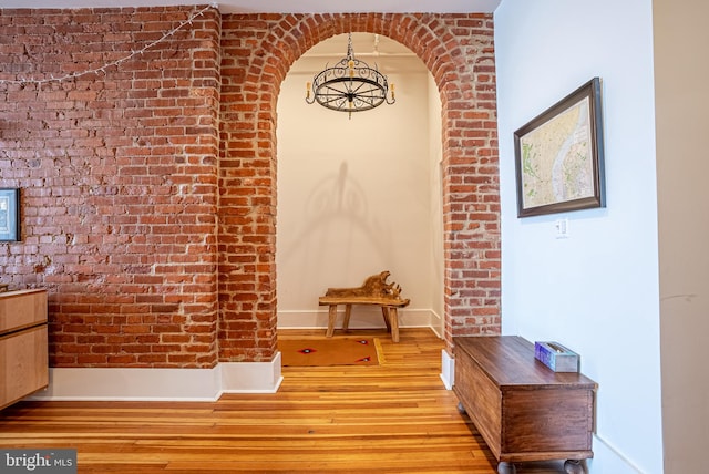 hall with brick wall and light hardwood / wood-style floors