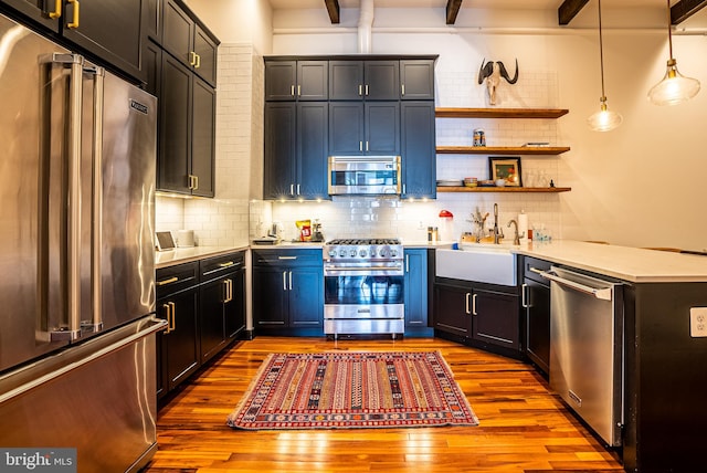 kitchen with pendant lighting, beamed ceiling, tasteful backsplash, premium appliances, and light hardwood / wood-style flooring