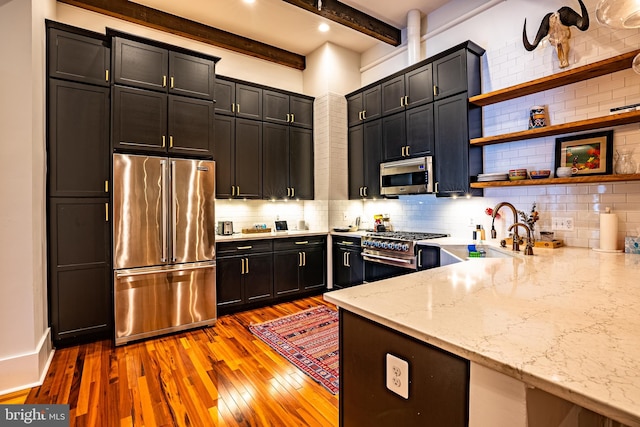 kitchen with beamed ceiling, light stone countertops, high end appliances, sink, and light hardwood / wood-style flooring