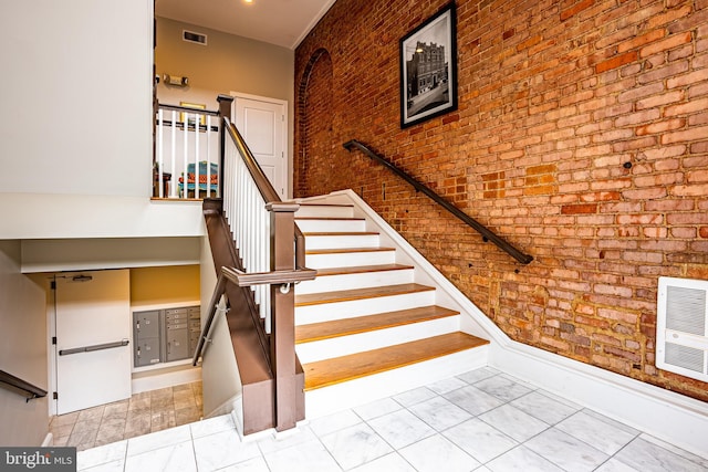 staircase featuring heating unit, brick wall, tile patterned floors, and mail boxes