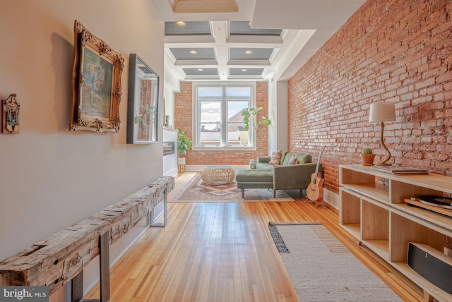 hallway with brick wall, coffered ceiling, light wood-type flooring, and beamed ceiling