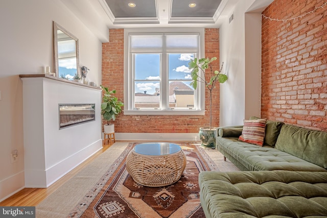 living room featuring wood-type flooring, brick wall, and a healthy amount of sunlight