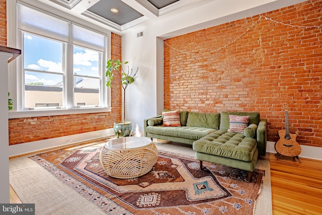 living room with hardwood / wood-style flooring, brick wall, coffered ceiling, ornamental molding, and beam ceiling