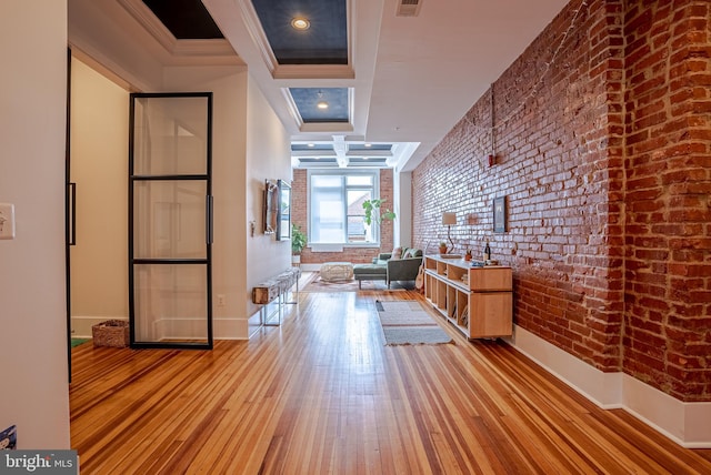 hallway featuring brick wall, crown molding, and light hardwood / wood-style floors