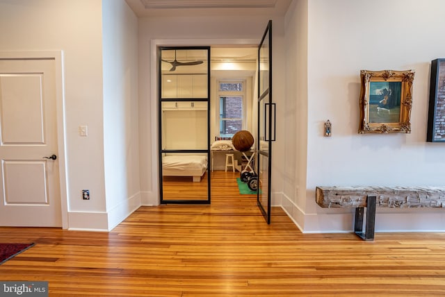 hall with ornamental molding and light wood-type flooring