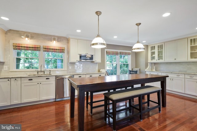 kitchen featuring pendant lighting, dark wood-type flooring, sink, backsplash, and appliances with stainless steel finishes