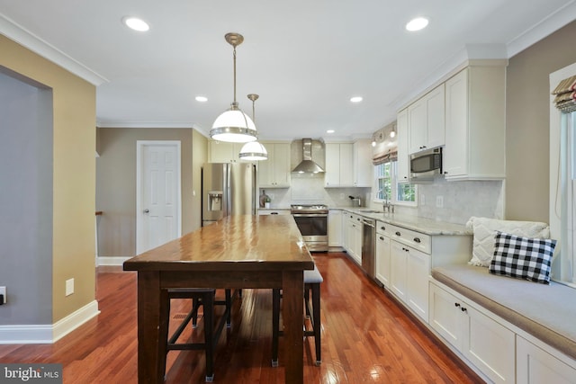 kitchen with stainless steel appliances, hardwood / wood-style floors, decorative light fixtures, and wall chimney exhaust hood