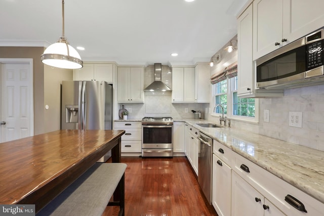 kitchen with sink, wall chimney exhaust hood, dark wood-type flooring, appliances with stainless steel finishes, and decorative backsplash