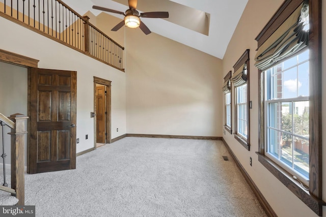 spare room featuring ceiling fan, light carpet, a healthy amount of sunlight, and high vaulted ceiling