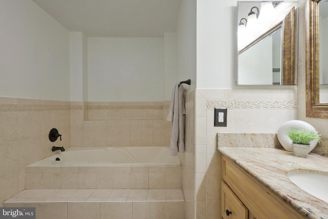 bathroom featuring a relaxing tiled tub, tile walls, and vanity