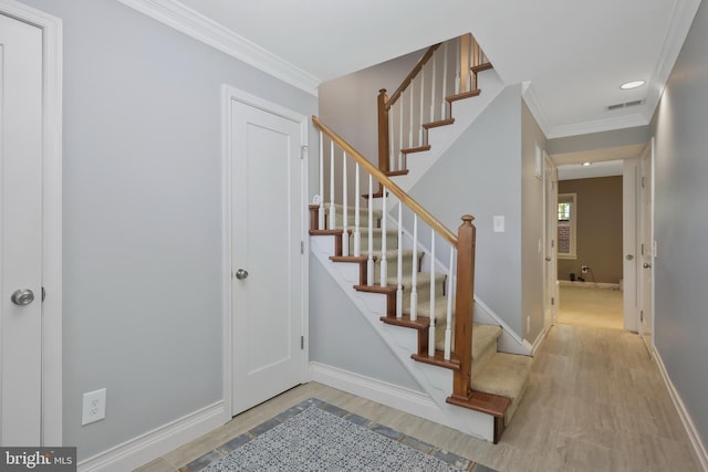 foyer entrance with crown molding and light hardwood / wood-style flooring