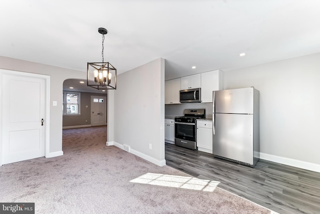 kitchen featuring white cabinets, stainless steel appliances, dark wood-type flooring, and decorative light fixtures