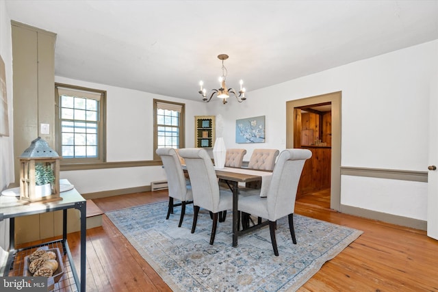 dining space with a notable chandelier, light hardwood / wood-style flooring, and a baseboard heating unit