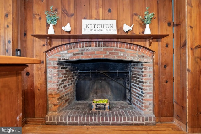 interior details with wood walls, wood-type flooring, and a fireplace