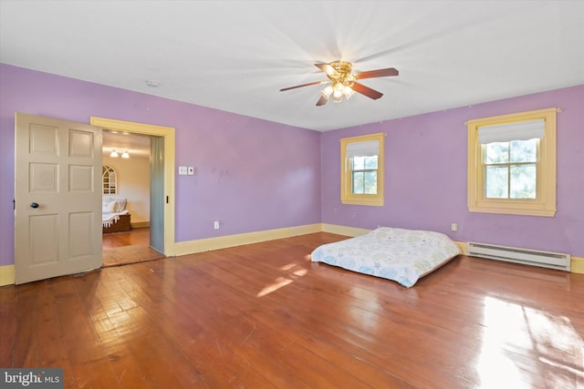 unfurnished bedroom with a baseboard heating unit, wood-type flooring, and ceiling fan