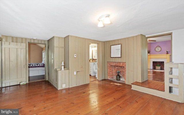 unfurnished living room with hardwood / wood-style floors, a fireplace, and wood walls