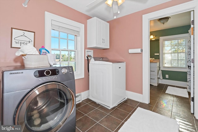 laundry area with dark tile patterned floors, cabinets, a baseboard radiator, washing machine and clothes dryer, and ceiling fan