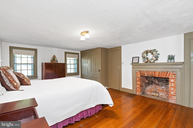 bedroom with a brick fireplace and hardwood / wood-style floors