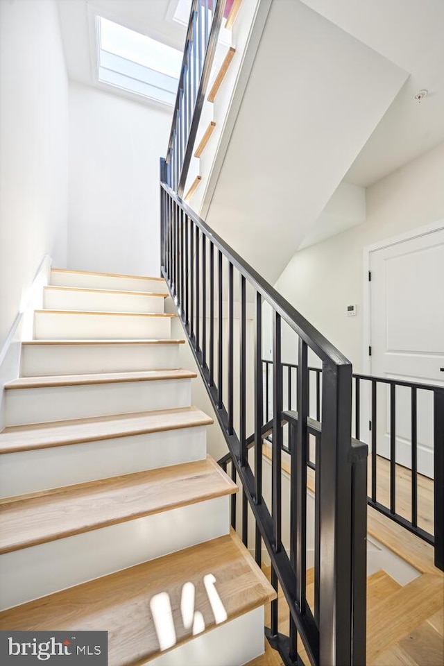 stairway featuring hardwood / wood-style flooring and a skylight