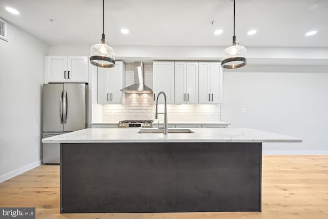 kitchen featuring wall chimney range hood, sink, appliances with stainless steel finishes, pendant lighting, and light stone counters