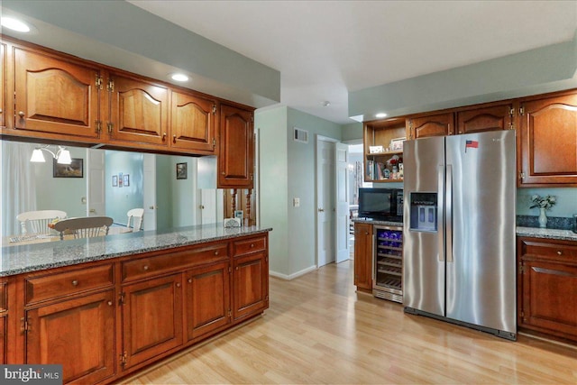 kitchen featuring beverage cooler, stainless steel refrigerator with ice dispenser, light stone counters, and light hardwood / wood-style flooring