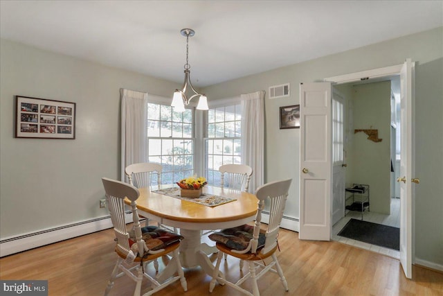 dining room with a notable chandelier, light hardwood / wood-style floors, and a baseboard heating unit