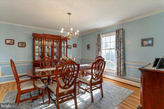 dining area featuring a chandelier, a baseboard radiator, light wood-type flooring, and crown molding