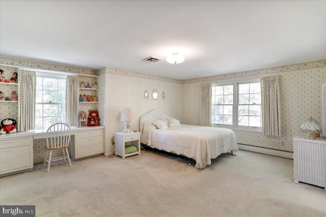 bedroom with a baseboard heating unit, light colored carpet, and built in desk