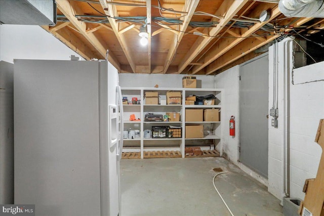 basement with white refrigerator with ice dispenser