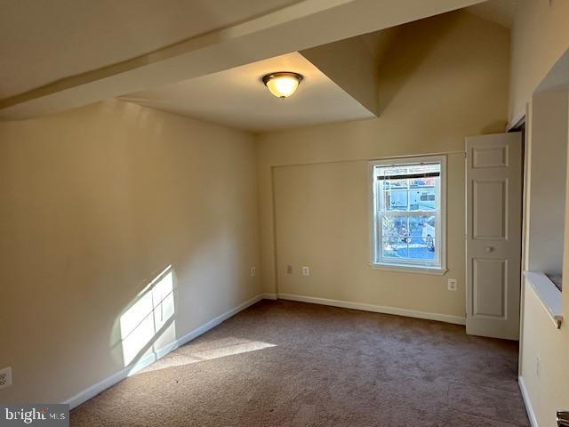 spare room featuring carpet flooring and baseboards