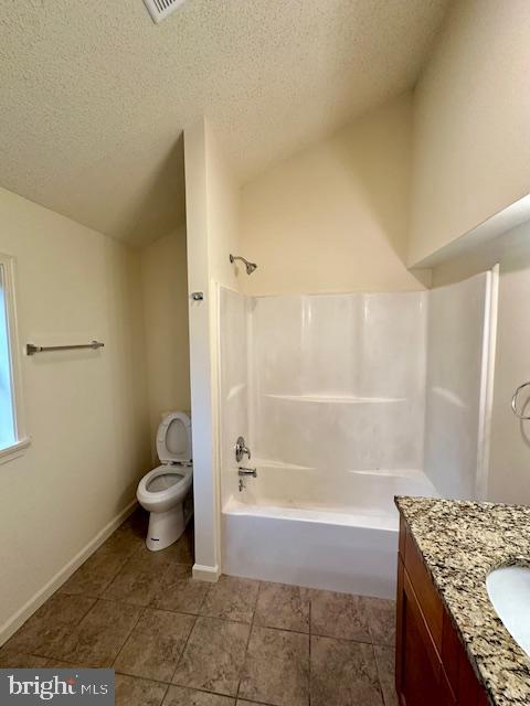 bathroom with a textured ceiling, vanity, tile patterned flooring, vaulted ceiling, and toilet