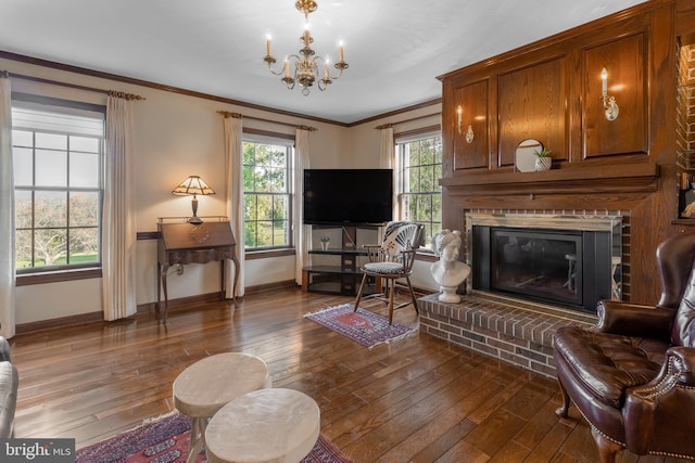 living room featuring ornamental molding, a fireplace, a notable chandelier, and dark wood-type flooring