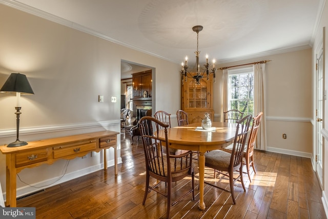 dining space featuring ornamental molding, dark wood-type flooring, and an inviting chandelier