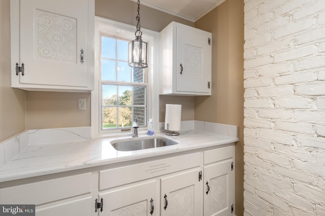 kitchen with pendant lighting, ornamental molding, white cabinets, and sink