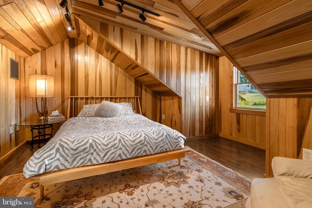 bedroom featuring hardwood / wood-style flooring, wooden walls, vaulted ceiling, and rail lighting