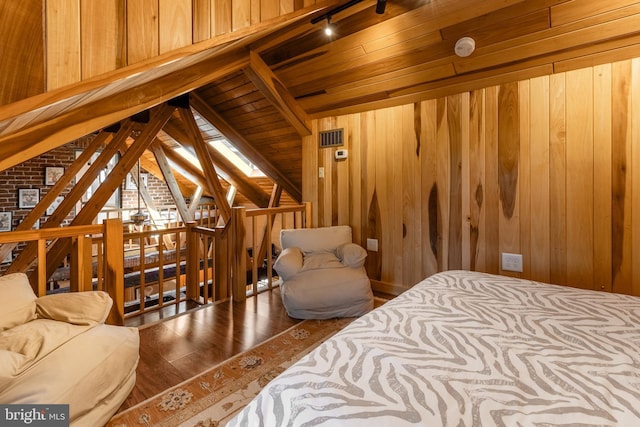 bedroom featuring lofted ceiling with beams, wooden walls, hardwood / wood-style floors, wood ceiling, and track lighting